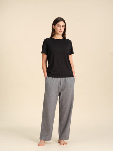 Woman wearing a T-shirts matching the grey heather merino wool straight-leg pant against a sand background.