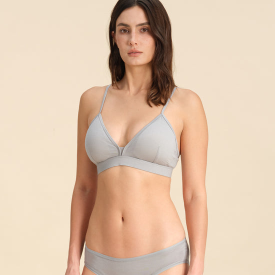 Woman wearing a grey triangle bra and bikini set against a sand background