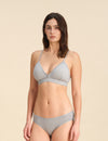 Woman wearing a grey triangle bra and bikini set against a sand background