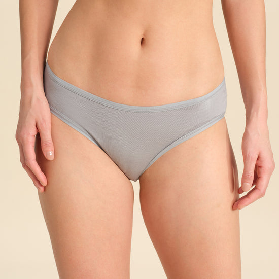 Person wearing grey bikini brief against a neutral background