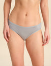 Person wearing grey bikini brief against a neutral background