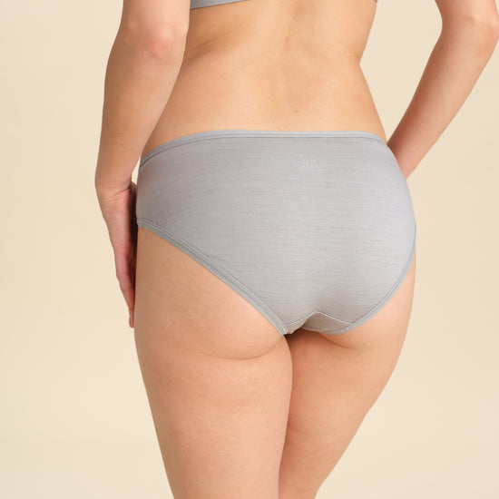 Back view of person wearing grey bikini brief against a neutral background