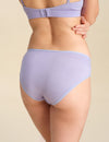 Back view of person wearing a lavender bikini brief against a sand background