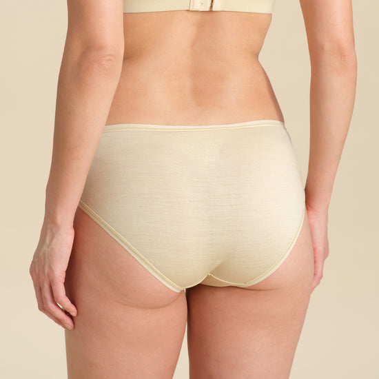 Back view of person wearing sand bikini brief against a neutral background.