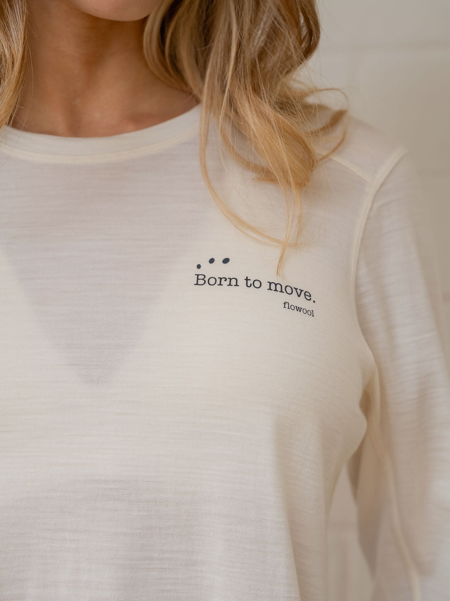 White long-sleeve shirt with 'Born to move' text on a neutral background