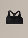 Women's black merino wool sports bra on a neutral sand background.