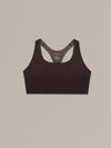 Women's chocolate merino wool sports bra on a neutral sand background.
