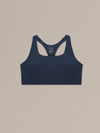 Women's navy merino wool sports bra on a neutral sand background.