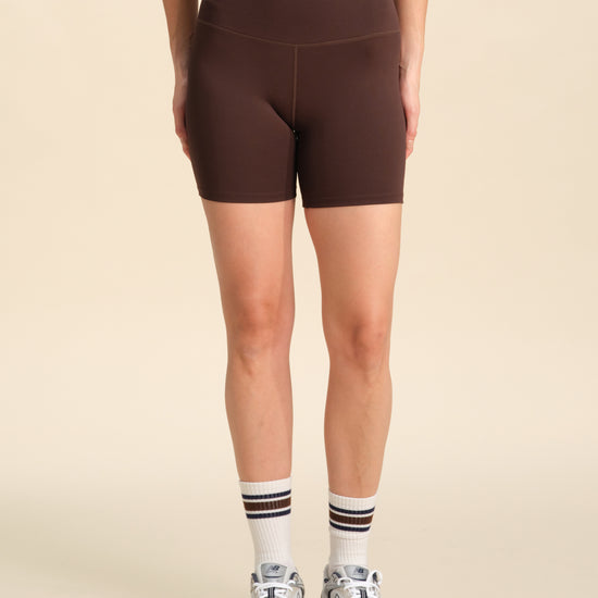 Person wearing chocolate flex sports shorts against a neutral background.