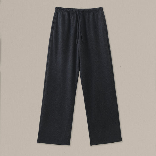 Women's black heather merino wool straight-leg pant on a neutral sand background.
