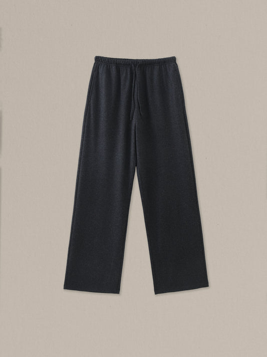 Women's black heather merino wool straight-leg pant on a neutral sand background.