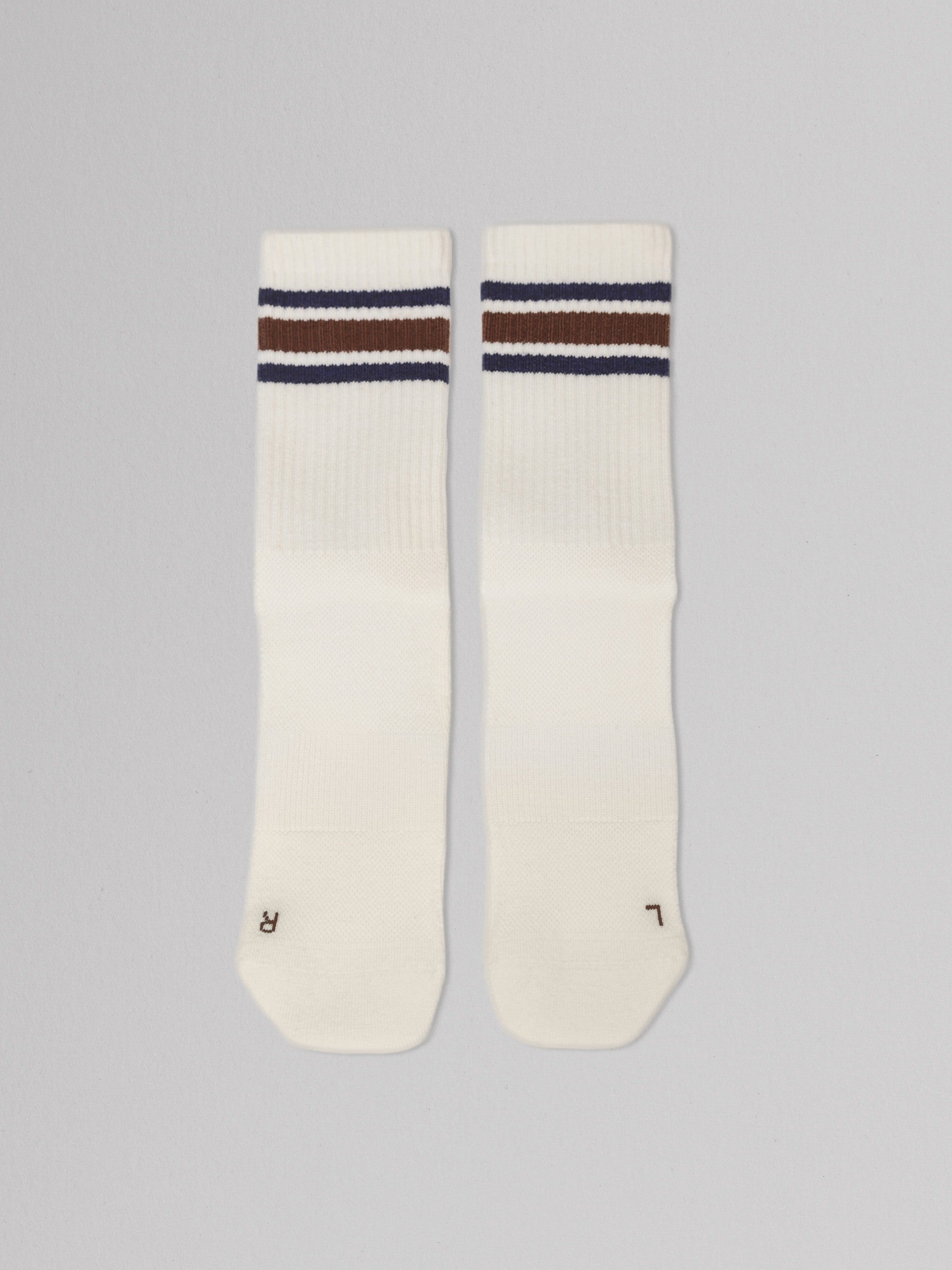 Two white socks with brown and blue stripes on a gray background