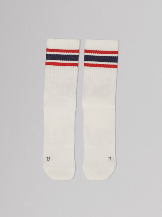 Pair of white socks with red and blue stripes on a gray background
