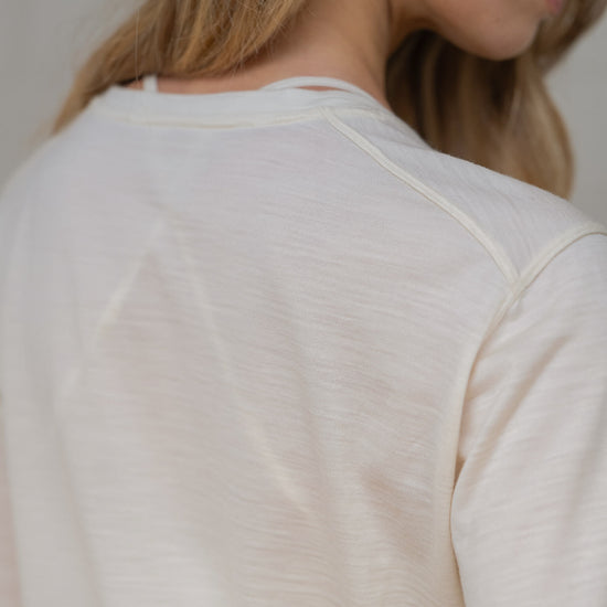 Close-up of a person wearing a light-colored long-sleeve shirt against a neutral background