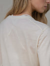 Close-up of a person wearing a light-colored long-sleeve shirt against a neutral background