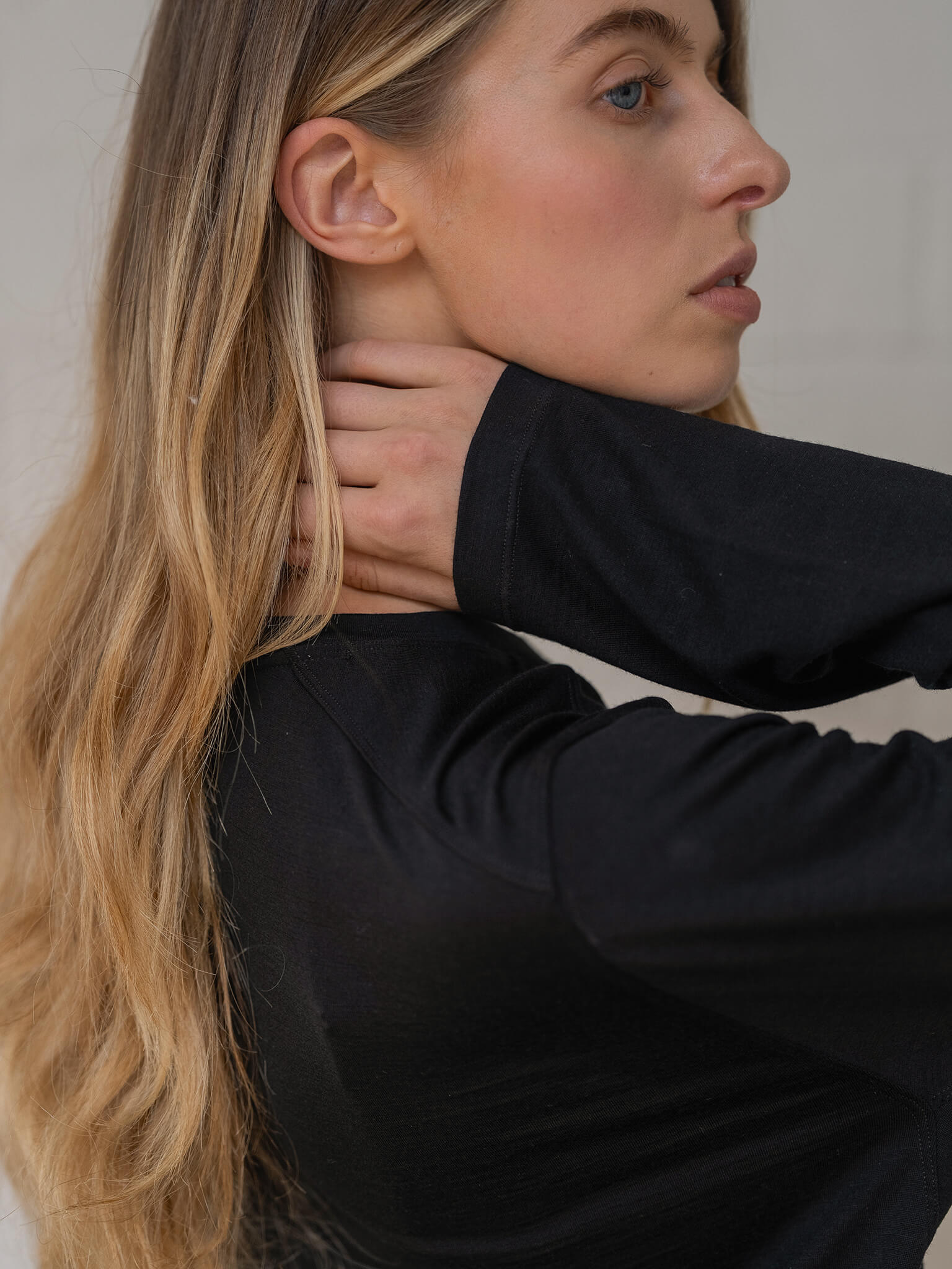 Woman with long blonde hair wearing a black top against a neutral background
