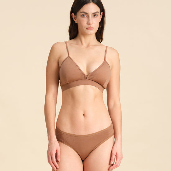 Woman wearing a cinnamon Merino wool triangle bra and underwear set against the background.