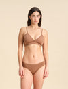 Woman wearing a cinnamon Merino wool triangle bra and underwear set against the background.