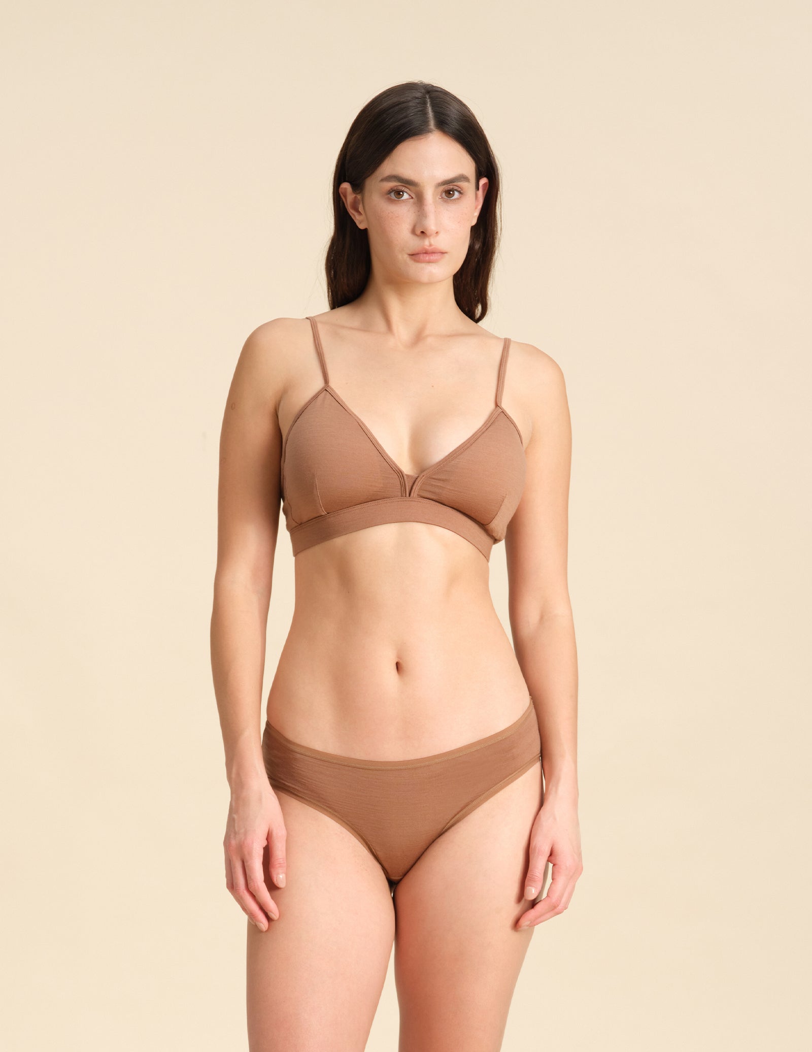 Woman wearing a cinnamon Merino wool triangle bra and underwear set against the background.