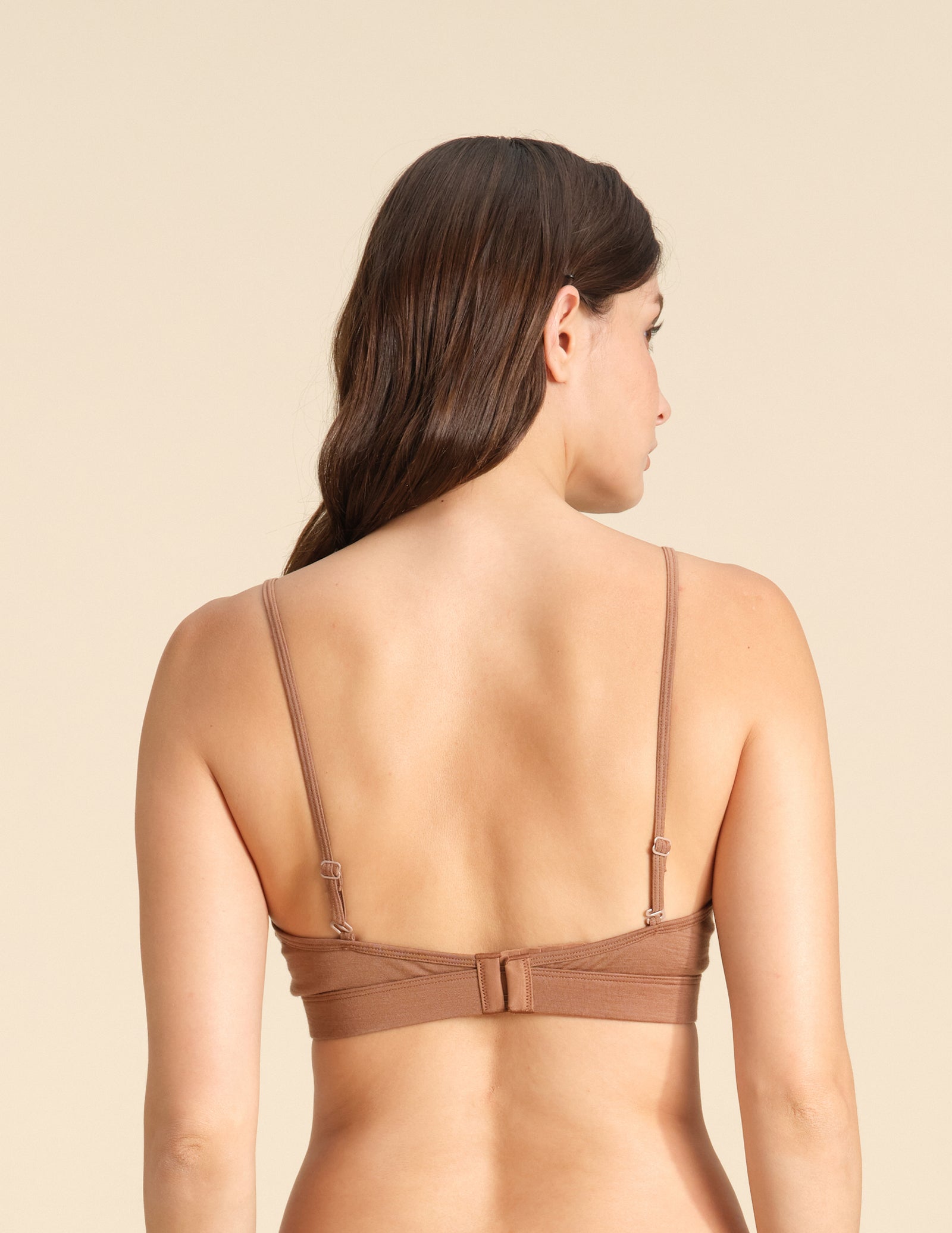 Back view of woman wearing a cinnamon Merino wool triangle bra  against the background.