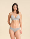 Woman wearing a grey Merino wool triangle bra and underwear set against the background.