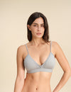 Woman wearing a grey Merino wool triangle bra against the background.