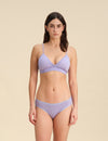 Woman wearing a lavender Merino wool triangle bra and underwear set against the background.
