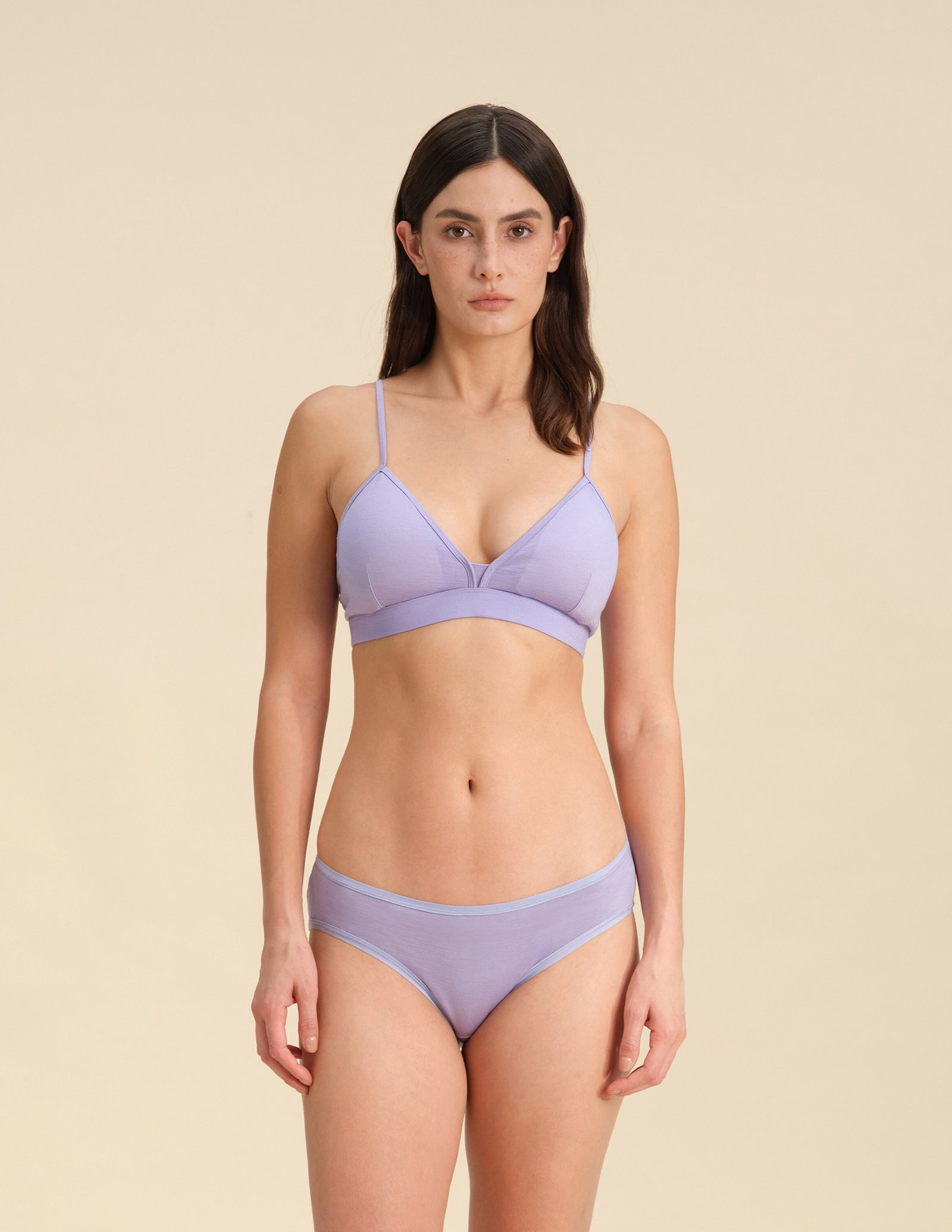 Woman wearing a lavender Merino wool triangle bra and underwear set against the background.