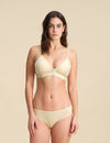 Woman wearing a sand Merino wool triangle bra and underwear set against the background.