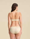 Back view of Woman wearing a sand Merino wool triangle bra and underwear set against the background