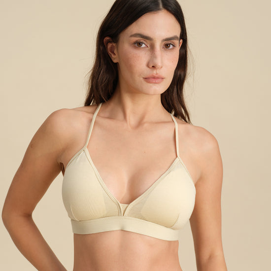 Woman wearing a sand Merino wool triangle bra against the background