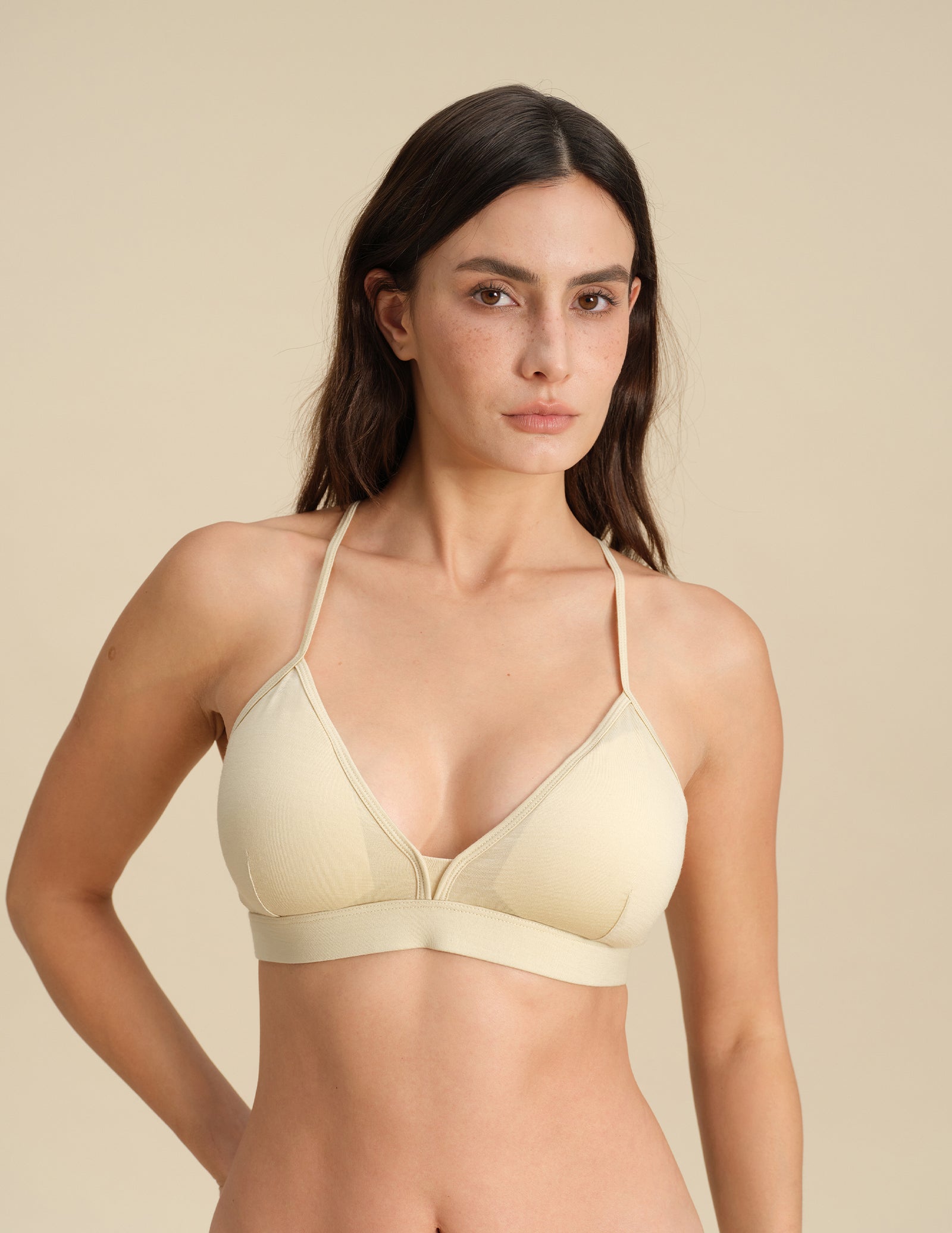Woman wearing a sand Merino wool triangle bra against the background
