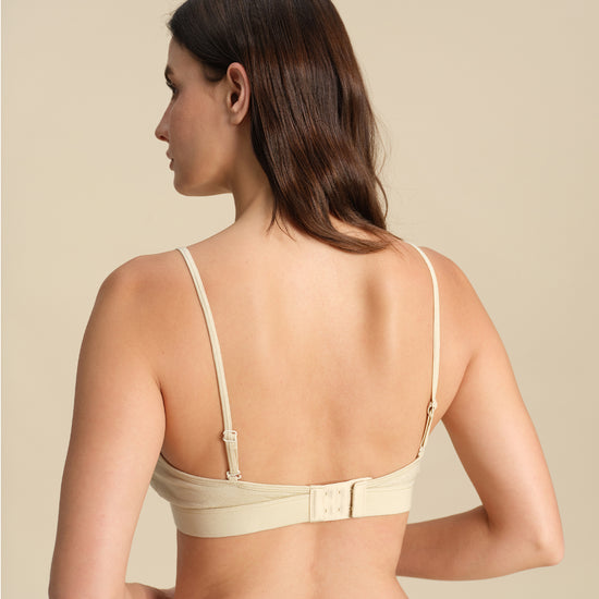 Back view of Woman wearing a sand Merino wool triangle bra against the background